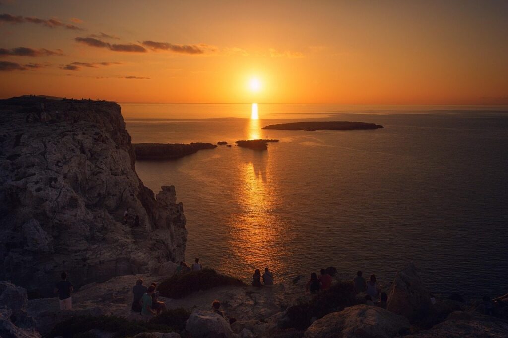 Farbintensiver Sonennuntergang vor Menorca mit Zuschauern